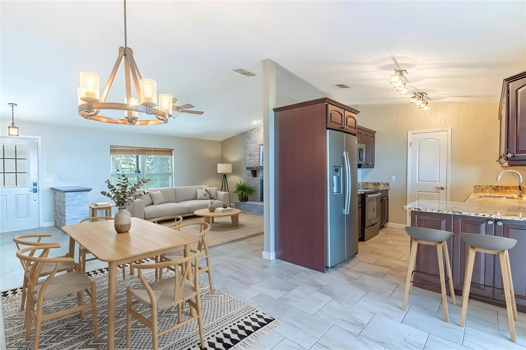 An open-concept living and dining area features a kitchen island, stainless appliances, and tile flooring — 715 S LAKESIDE TERRACE, EAGLE LAKE, FL