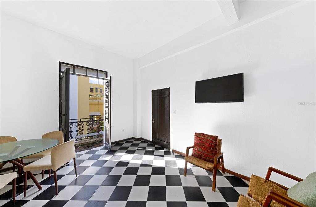 A living and dining area features black-and-white checkered floors, white walls, and a balcony door — 103 CRISTO STREET, SAN JUAN, PR