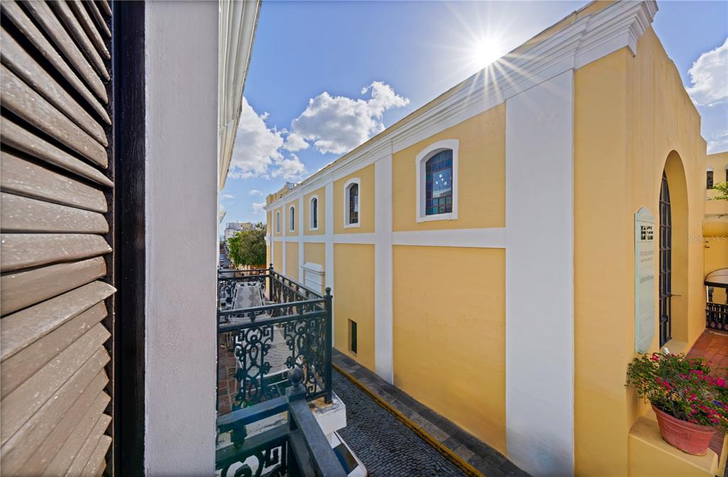 A view from a balcony overlooking a narrow cobblestone street beside a yellow building — 103 CRISTO STREET, SAN JUAN, PR