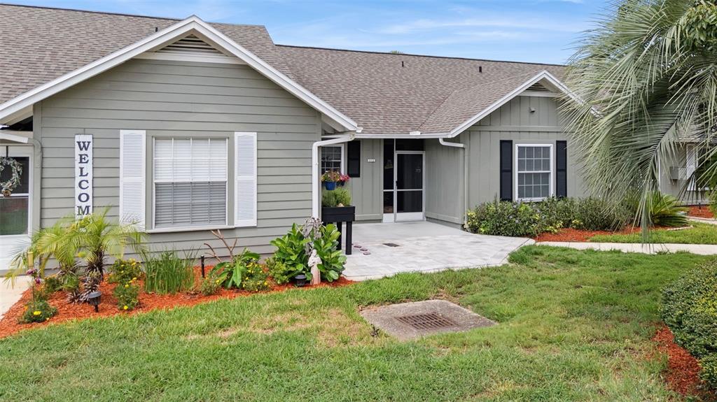A light green house with a front patio, white shutters, and a landscaped yard — 1112 VILLA LANE UNIT 84, APOPKA, FL