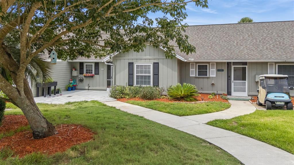 A single-story house with light green siding, a concrete walkway, and a golf cart parked outside — 1112 VILLA LANE UNIT 84, APOPKA, FL
