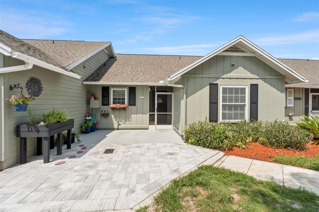 A light green house exterior features a paved patio, a screened entryway, and window boxes — 1112 VILLA LANE UNIT 84, APOPKA, FL