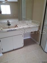 A bathroom vanity with a white cabinet, tiled countertop, and a large mirror — 2 PERTHSHIRE LANE, PALM COAST, FL