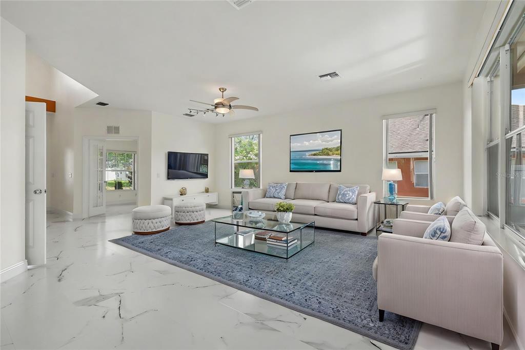 A bright living room features white marble floors, a blue area rug, and neutral furniture — 4014 SW 51ST COURT, OCALA, FL