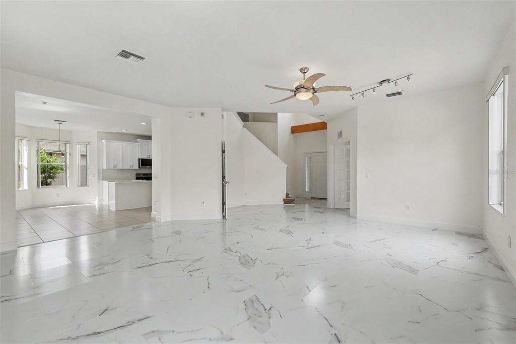 A spacious living room features white marble-look tile flooring, a ceiling fan, and recessed lighting — 4014 SW 51ST COURT, OCALA, FL