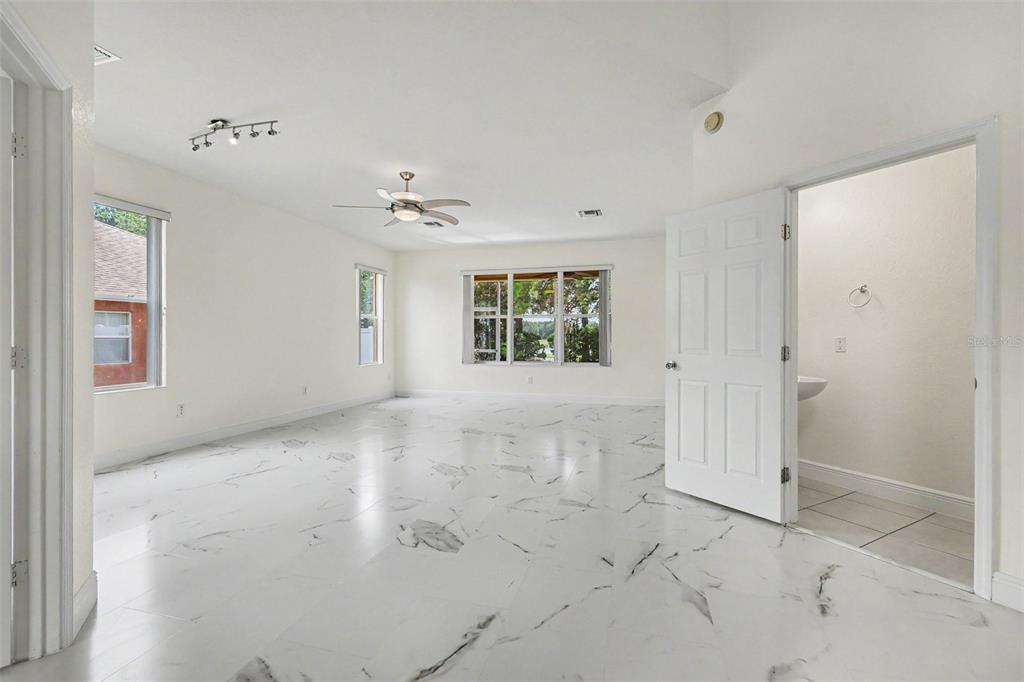 A bright room with white marble-look tile flooring, a ceiling fan, and an attached bathroom — 4014 SW 51ST COURT, OCALA, FL