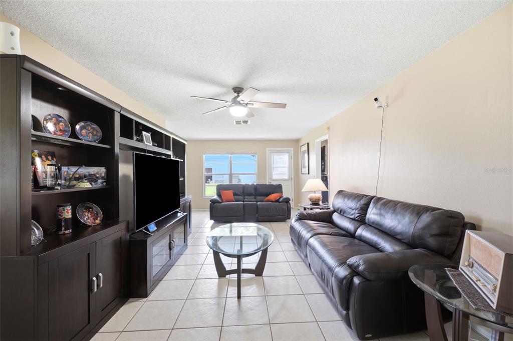 A living room features a large entertainment center, two leather sofas, and tile flooring — 4903 LEYTE COURT UNIT 67, NEW PORT RICHEY, FL