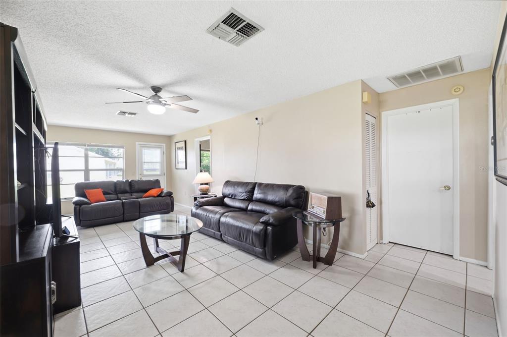 A living room features white tile floors, two dark leather sofas, and a glass coffee table — 4903 LEYTE COURT UNIT 67, NEW PORT RICHEY, FL