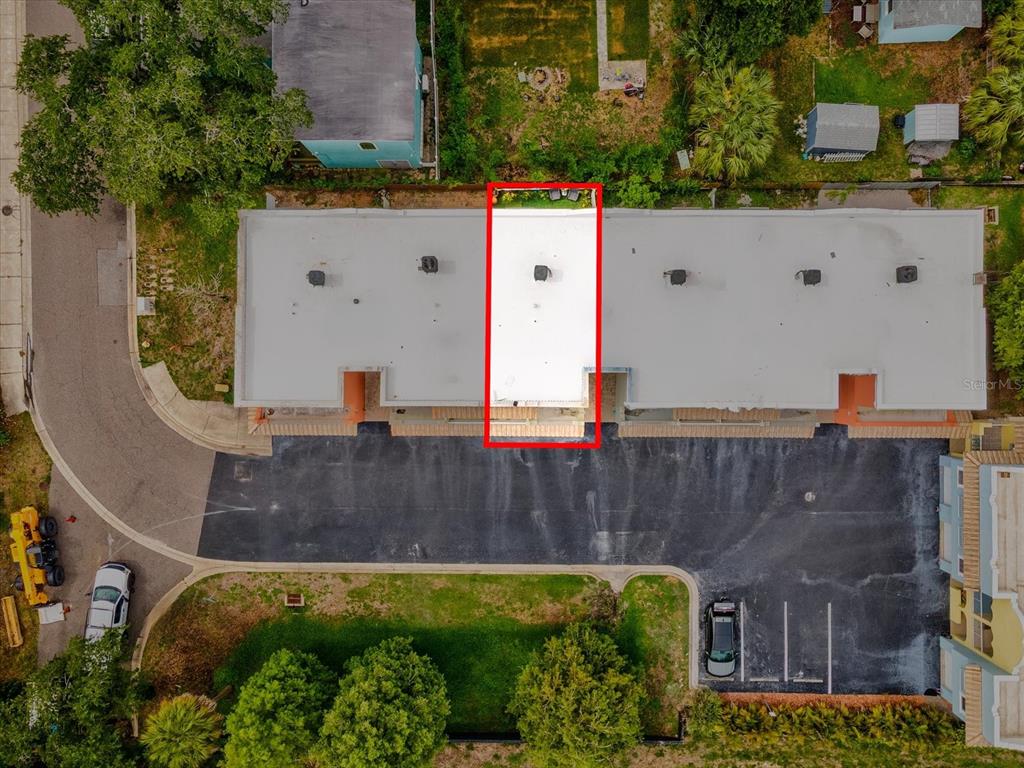 An aerial view shows a multi-unit building with a highlighted section featuring a white roof — 553 LUSARA COURT, DUNEDIN, FL