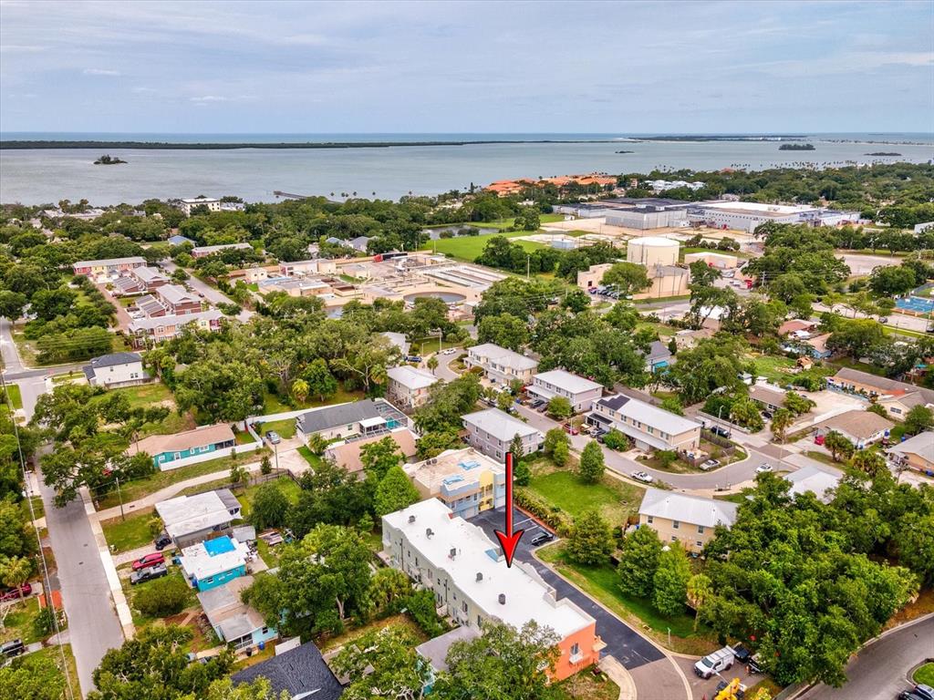 An aerial view shows a multi-story apartment building with a red arrow pointing to it — 553 LUSARA COURT, DUNEDIN, FL
