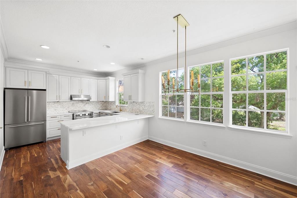 A kitchen with white cabinets, stainless steel appliances, a marble island, and hardwood floors — 2605 ESPANA COURT, TAMPA, FL