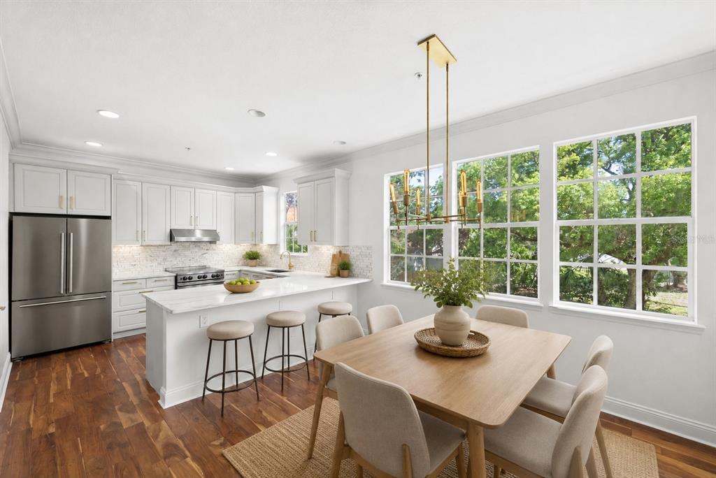 A bright kitchen and dining area with white cabinets, stainless appliances, and large windows — 2605 ESPANA COURT, TAMPA, FL