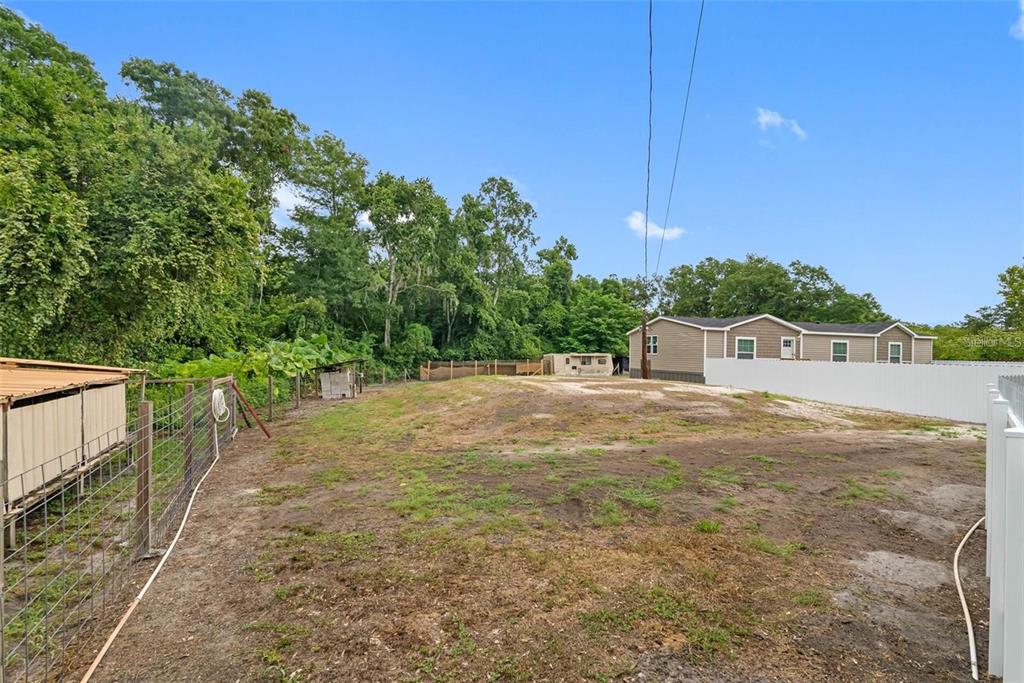 A large, grassy, fenced-in backyard features a small shed and a neighboring manufactured home — 17151 LEMON STREET, SPRING HILL, FL