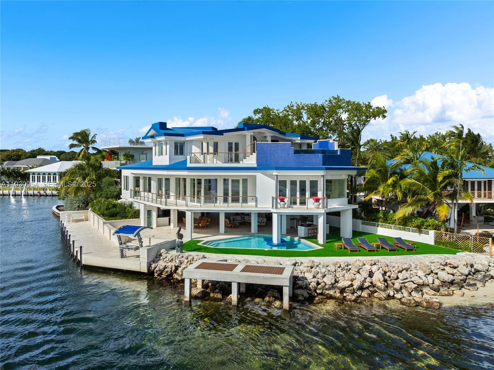 An aerial view of a multi-story waterfront house with a pool, deck, and private dock — 180 Pompano Dr, Key Largo FL 33037, KEY LARGO, FL