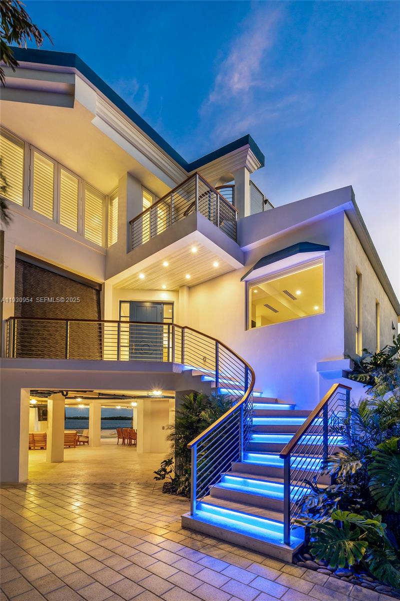 An exterior view of a modern house featuring a curved staircase with blue LED lighting — 180 Pompano Dr, Key Largo FL 33037, KEY LARGO, FL