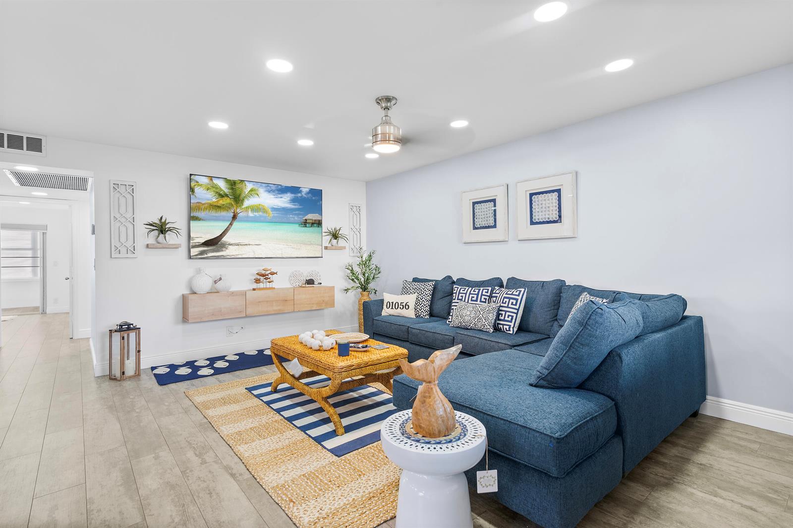 A living room features a blue sectional sofa, a wicker coffee table, and a wall-mounted television — 244 Monaco F, Delray Beach FL 33446, DELRAY BEACH, FL