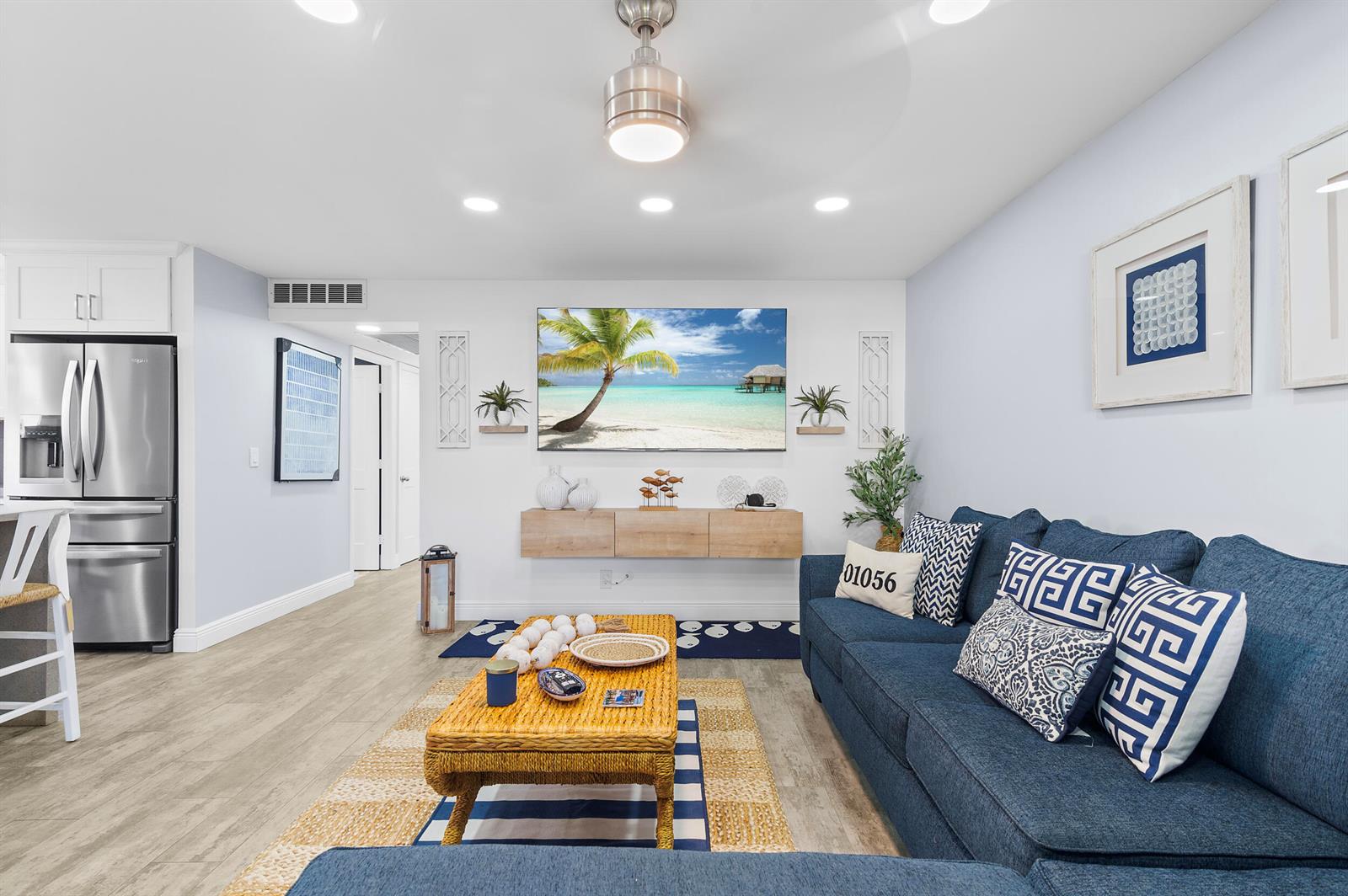 A living room features a blue sectional sofa, a wall-mounted television, and a wooden coffee table — 244 Monaco F, Delray Beach FL 33446, DELRAY BEACH, FL