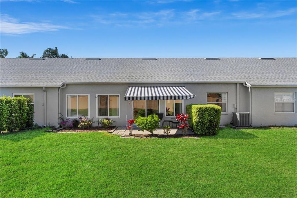The exterior of a single-story house features a striped awning over a sliding glass door — 6381 EGRET DRIVE UNIT 19, LAKELAND, FL