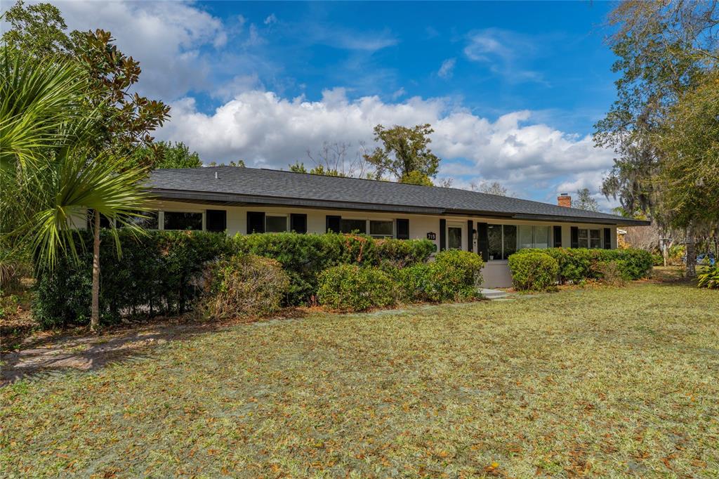A single-story ranch-style house with a dark roof, white siding, and mature landscaping — 715 EASTOVER CIR CIRCLE, DELAND, FL