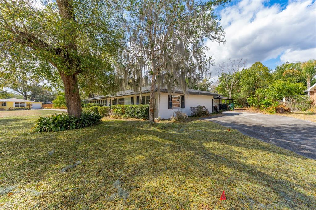 A single-story house with a white exterior, a paved driveway, and large trees in front — 715 EASTOVER CIR CIRCLE, DELAND, FL
