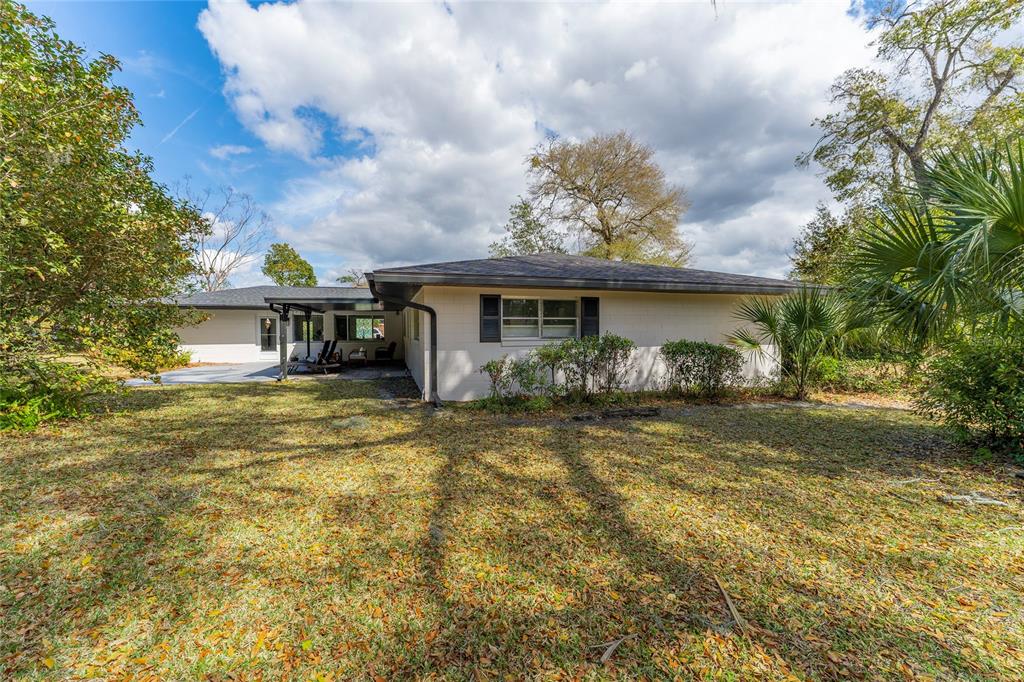 The exterior of a single-story house with a covered patio and a large grassy yard — 715 EASTOVER CIR CIRCLE, DELAND, FL