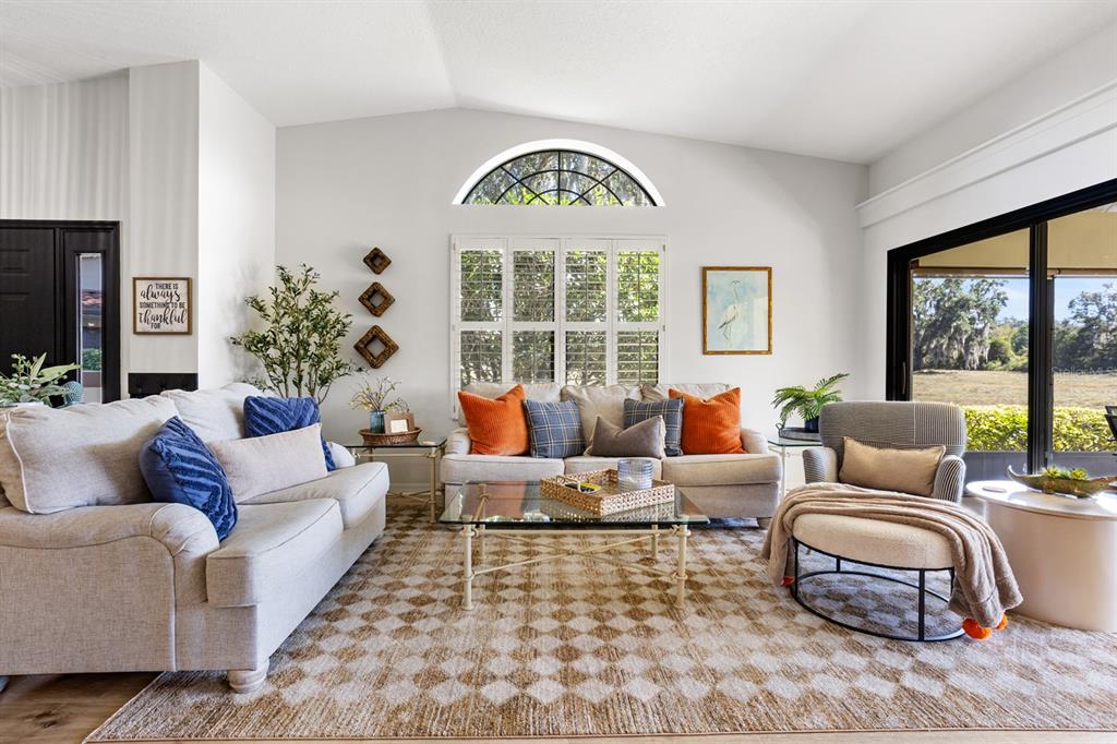 A living room features a vaulted ceiling, a patterned rug, and a large arched window — 138 STRATFORD COURT, HAINES CITY, FL