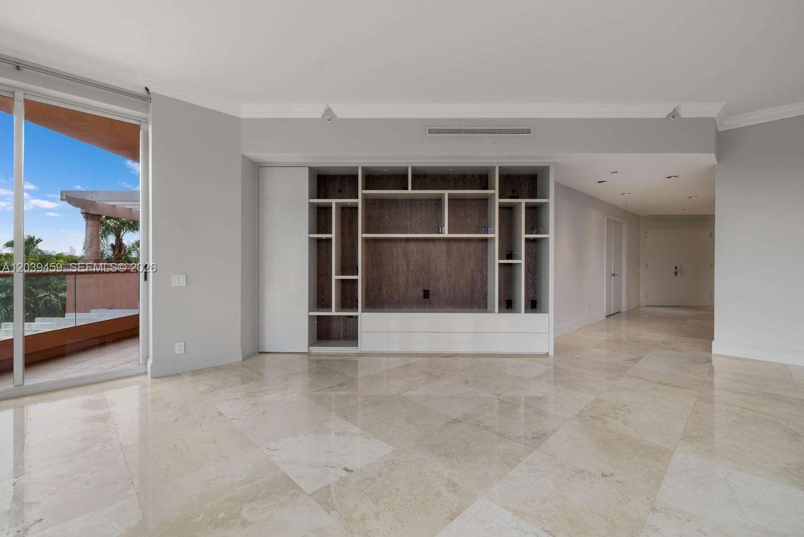 A living room features a large built-in media unit, marble flooring, and a glass balcony door — 10 Edgewater Dr # 4H, Coral Gables FL 33133, CORAL GABLES, FL
