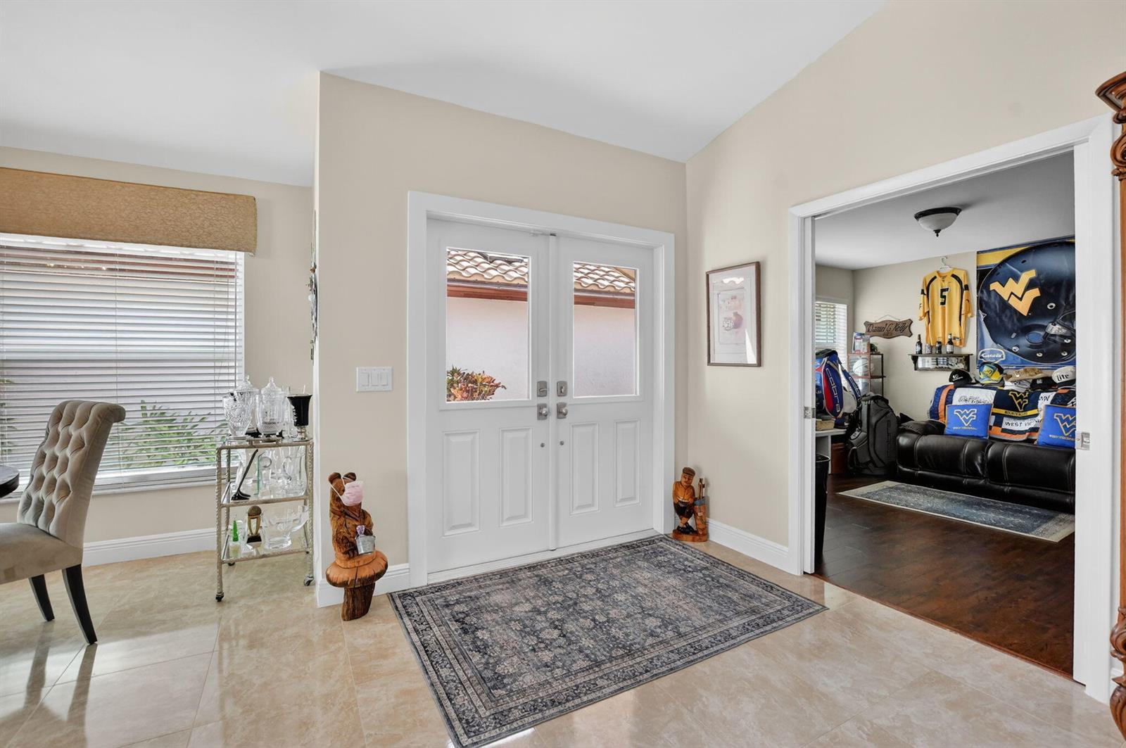 An entryway with a double front door, tile flooring, and an adjacent room with sports decor — 11270 Clover Leaf Circle, Boca Raton FL 33428, BOCA RATON, FL