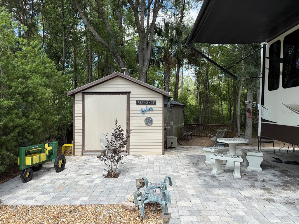 A shed with a patio, outdoor furniture, and a parked RV in a wooded area — 2853 NE 104TH TERRACE, SILVER SPRINGS, FL