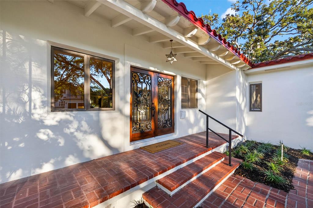 A brick porch with steps leads to a wooden double door with decorative iron grilles — 1222 BRIGHTWATERS BOULEVARD NE, ST PETERSBURG, FL