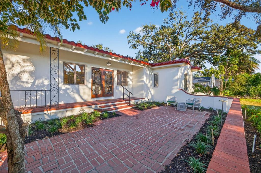 A brick patio sits in front of a white house with a red tile roof — 1222 BRIGHTWATERS BOULEVARD NE, ST PETERSBURG, FL