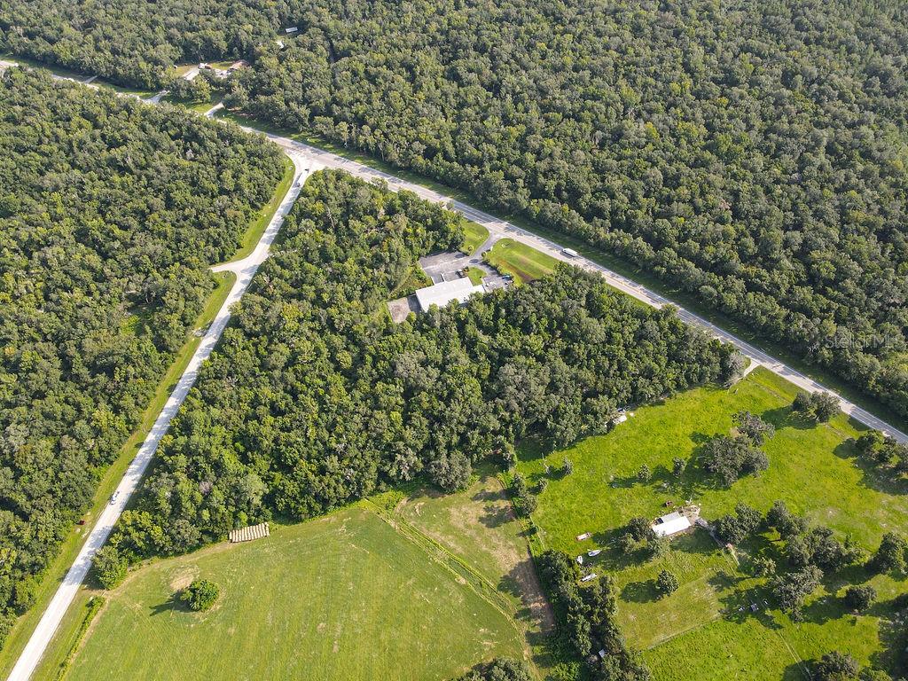 An aerial view shows a rural property with a building, forest, and open pasture land — PONCE DE LEON BOULEVARD, BROOKSVILLE, FL