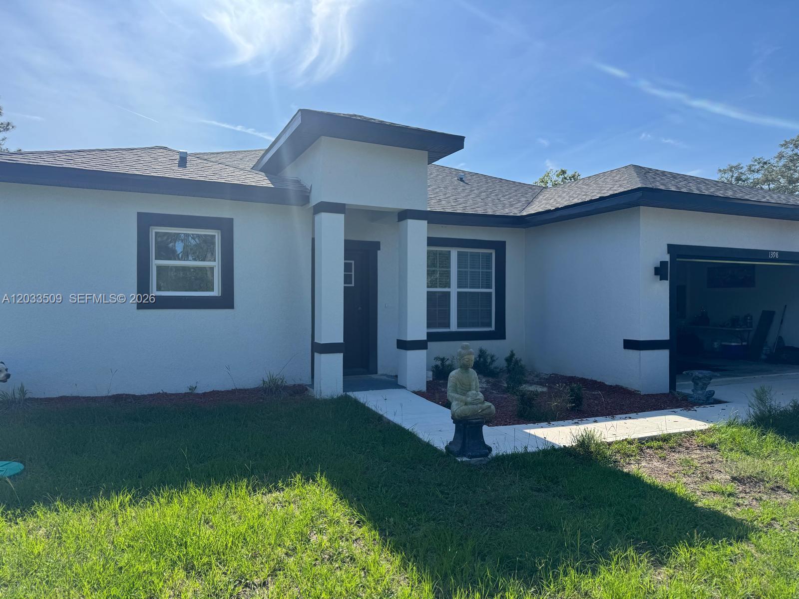 A white single-story house features dark trim, a covered entryway, and a two-car garage — 1398 SW Breezy Point Drive, Ocala FL 34431, OCALA, FL
