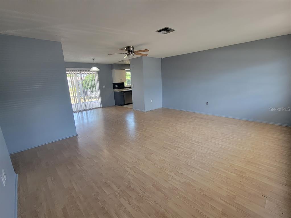An open-concept living area features light wood flooring, gray walls, and a ceiling fan — 22329 NIAGARA AVENUE, PORT CHARLOTTE, FL