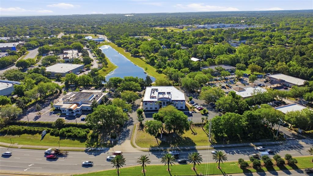 An aerial view shows commercial office buildings, a central pond, and a multi-lane road — 1690 DUNLAWTON AVENUE UNIT 130, PORT ORANGE, FL