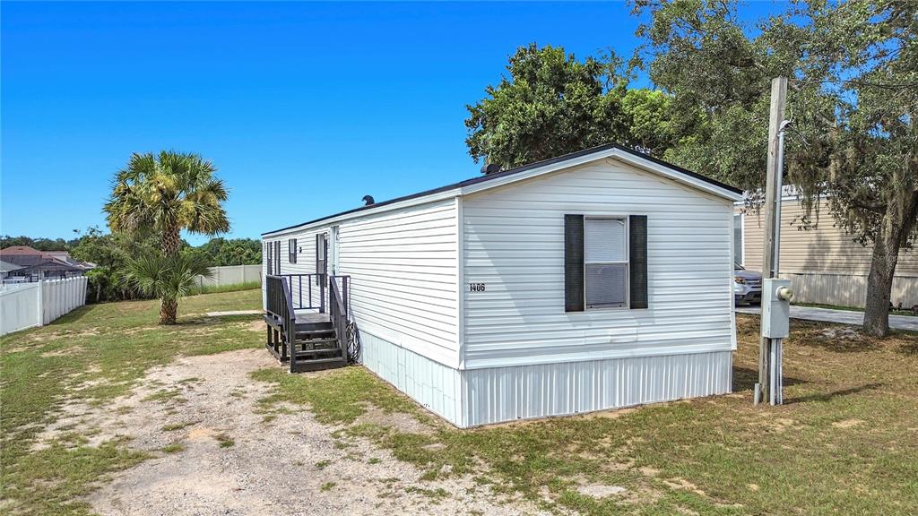 A white mobile home with a small wooden porch stands on a grassy lot — 1406 FINNEY ROAD, DAVENPORT, FL