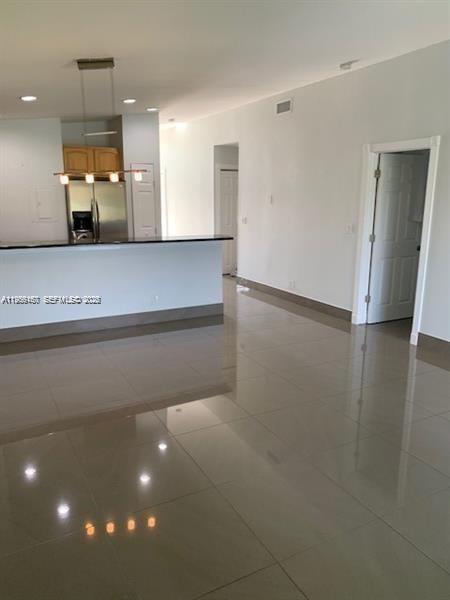 An open-concept kitchen with a breakfast bar and tile flooring leads into a hallway — 504 Woodgate Cir # C, Sunrise FL 33326, SUNRISE, FL