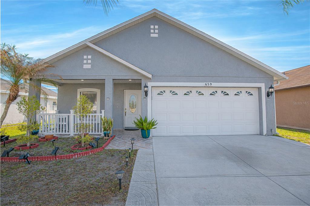 A single-story house with a gray stucco exterior, a two-car garage, and a front porch — 659 CALADESI TRAIL, ORLANDO, FL