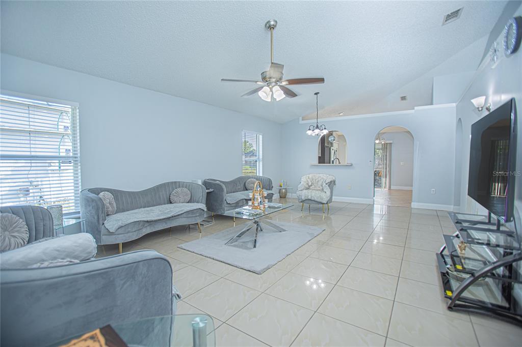 A living room features light gray walls, tiled floors, velvet sofas, and a ceiling fan — 659 CALADESI TRAIL, ORLANDO, FL