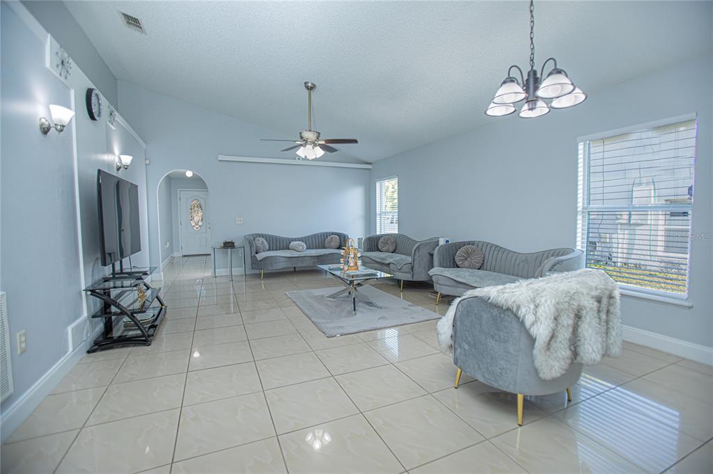 A living room features light blue walls, tile flooring, gray curved sofas, and a chandelier — 659 CALADESI TRAIL, ORLANDO, FL