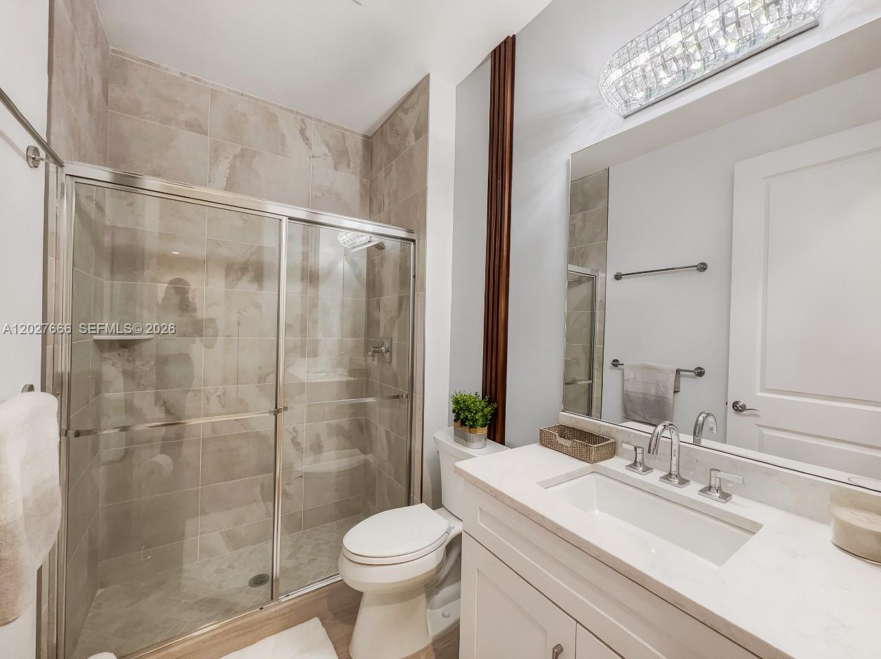 A bathroom features a glass-enclosed shower, a white vanity with a marble countertop, and tile — NAPLES, FL