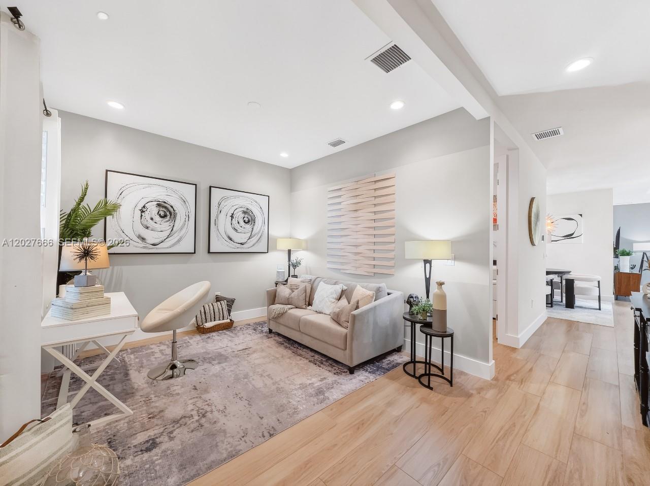 A modern living room features a gray sofa, a white desk, and abstract wall art — NAPLES, FL