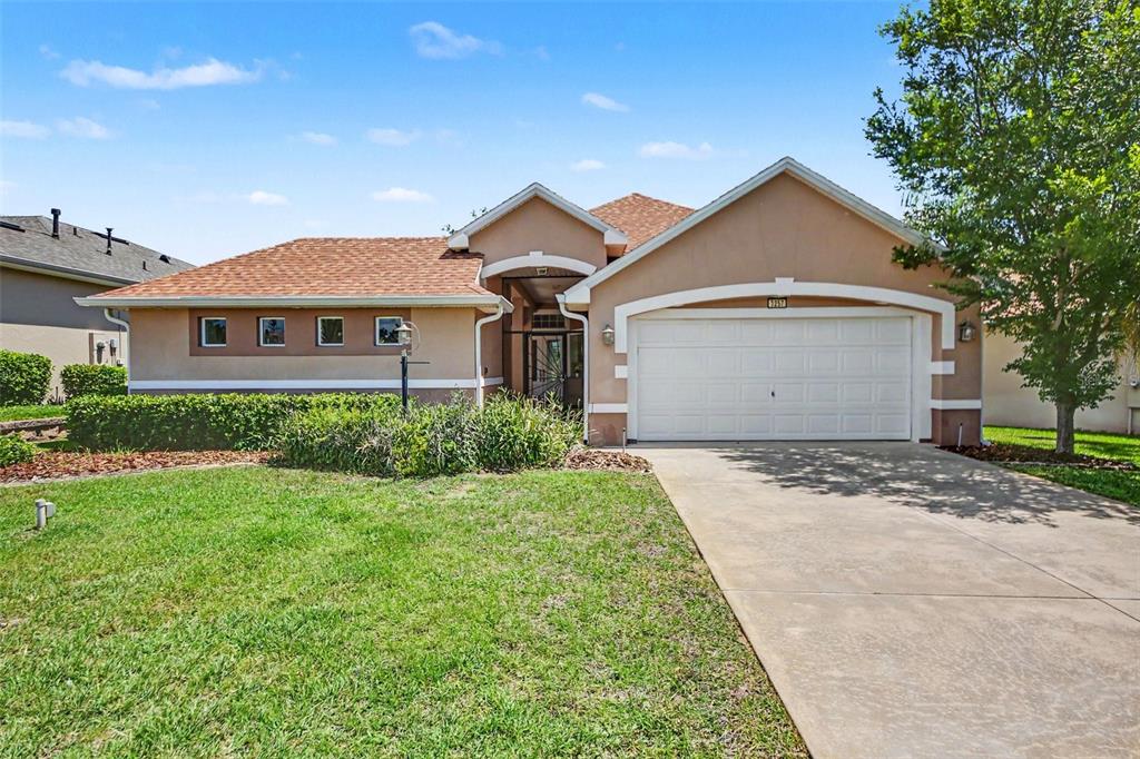 A single-story house with a tan stucco exterior, a two-car garage, and a shingled roof — 3257 BALTIC SEA BOULEVARD, TAVARES, FL