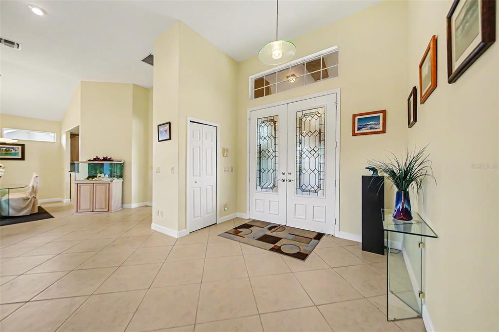 A bright foyer features tile flooring, double glass-paneled entry doors, and a high vaulted ceiling — 3257 BALTIC SEA BOULEVARD, TAVARES, FL