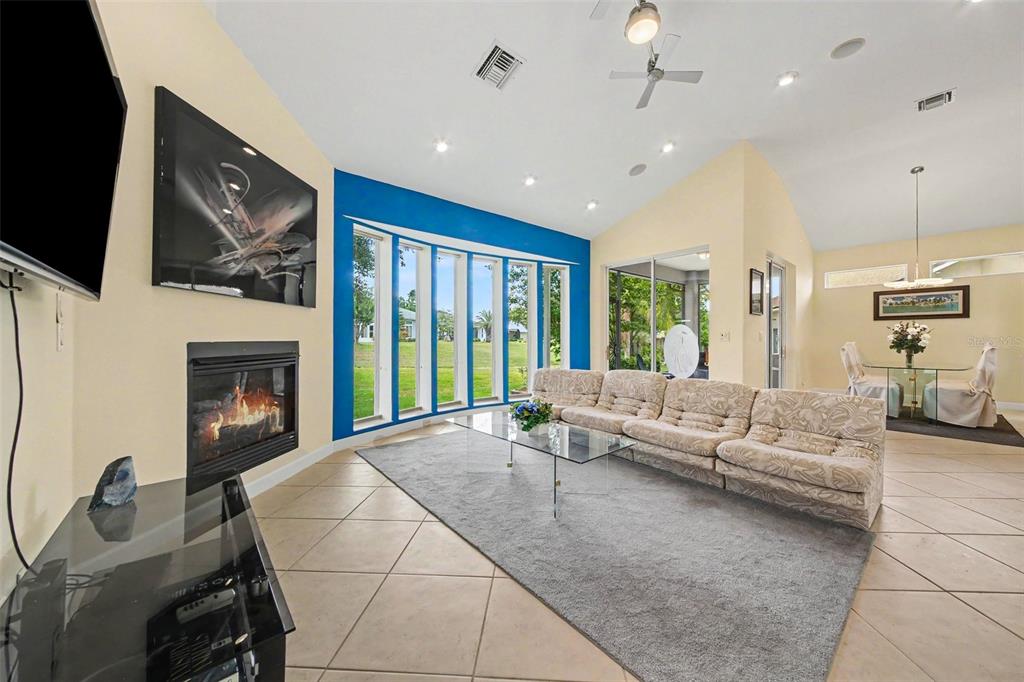 A living room features a fireplace, a large blue accent wall, and tile flooring — 3257 BALTIC SEA BOULEVARD, TAVARES, FL