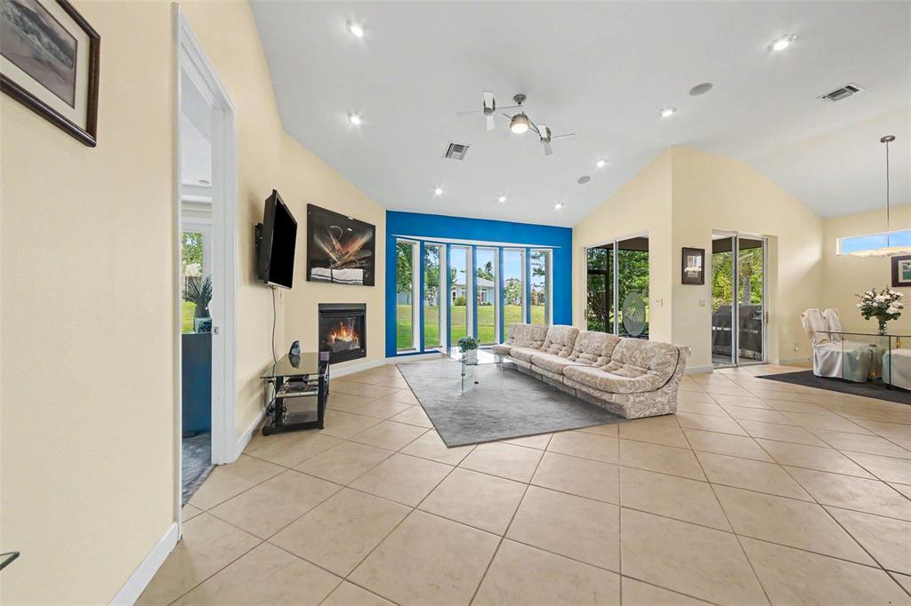 A living room features a fireplace, a large sectional sofa, and floor-to-ceiling windows — 3257 BALTIC SEA BOULEVARD, TAVARES, FL