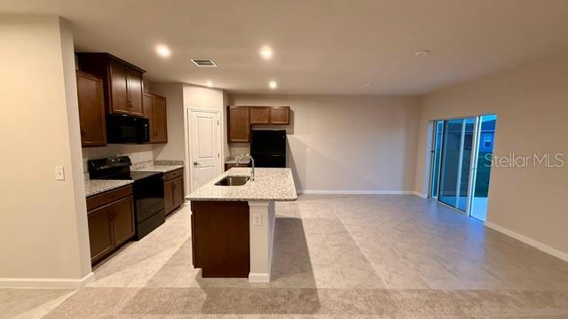 A kitchen with dark wood cabinets, granite countertops, a center island, and tile flooring — 1607 TEXAS AVENUE, SUMTERVILLE, FL