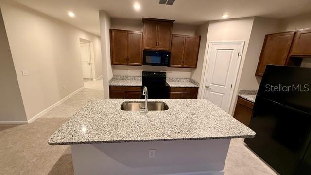 A kitchen with dark wood cabinets, granite countertops, a center island, and black appliances — 1607 TEXAS AVENUE, SUMTERVILLE, FL