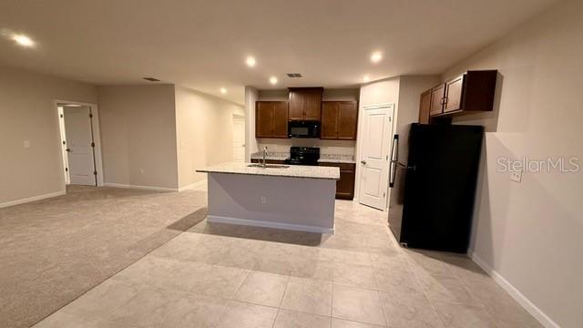 A kitchen with dark wood cabinets, a granite island, and a black refrigerator — 1607 TEXAS AVENUE, SUMTERVILLE, FL