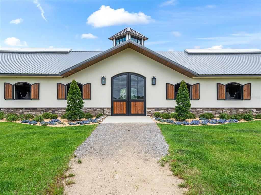 A single-story building with a metal roof, central cupola, and arched wooden stable doors — 2380 NW 72ND COURT, OCALA, FL